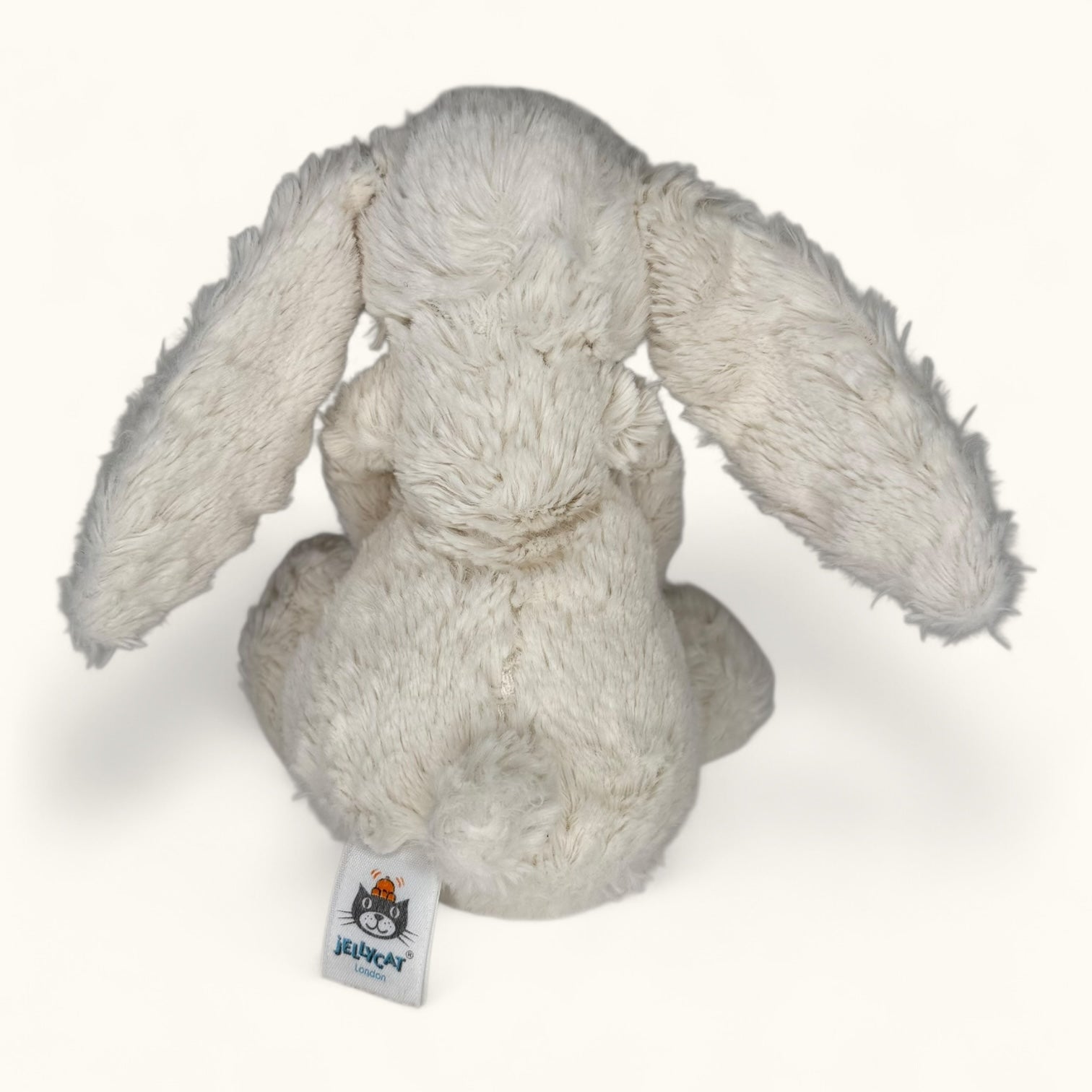 Plush rabbit toy with a visible brand tag on a white background