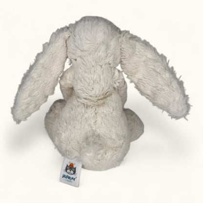 Plush rabbit toy with a visible brand tag on a white background