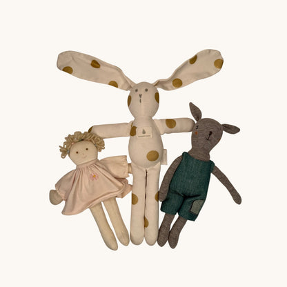 Set of three soft toys including a polka-dotted doll, a green rabbit, and a beige fairy on a white background