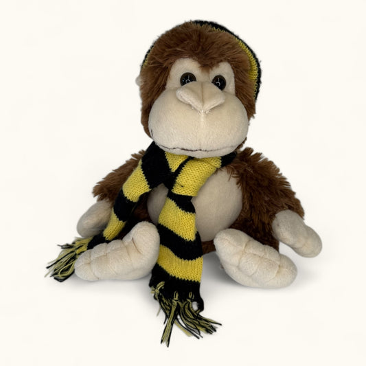 Plush monkey toy with a yellow and black striped scarf on a white background
