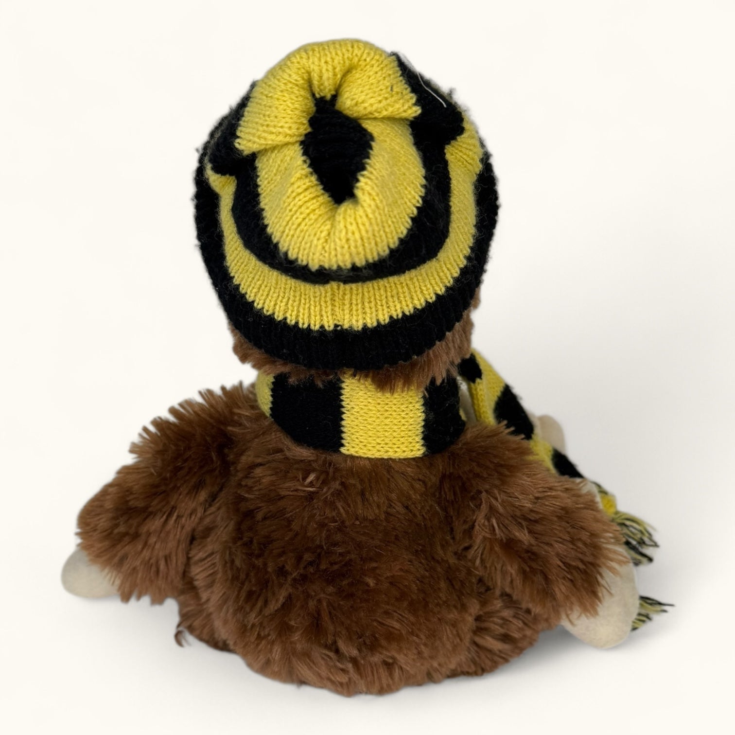 Plush toy monkey wearing a yellow and black striped sweater on a white background