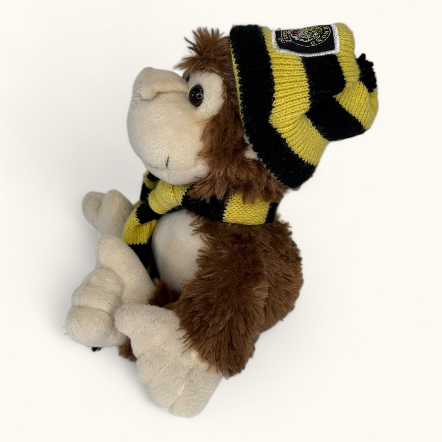 Plush toy monkey wearing a striped hat and scarf on a white background