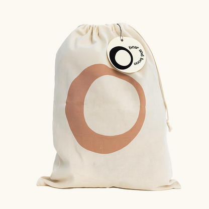 Beige drawstring bag with a large brown circle and a brand tag on a white background for re-homed soft toy